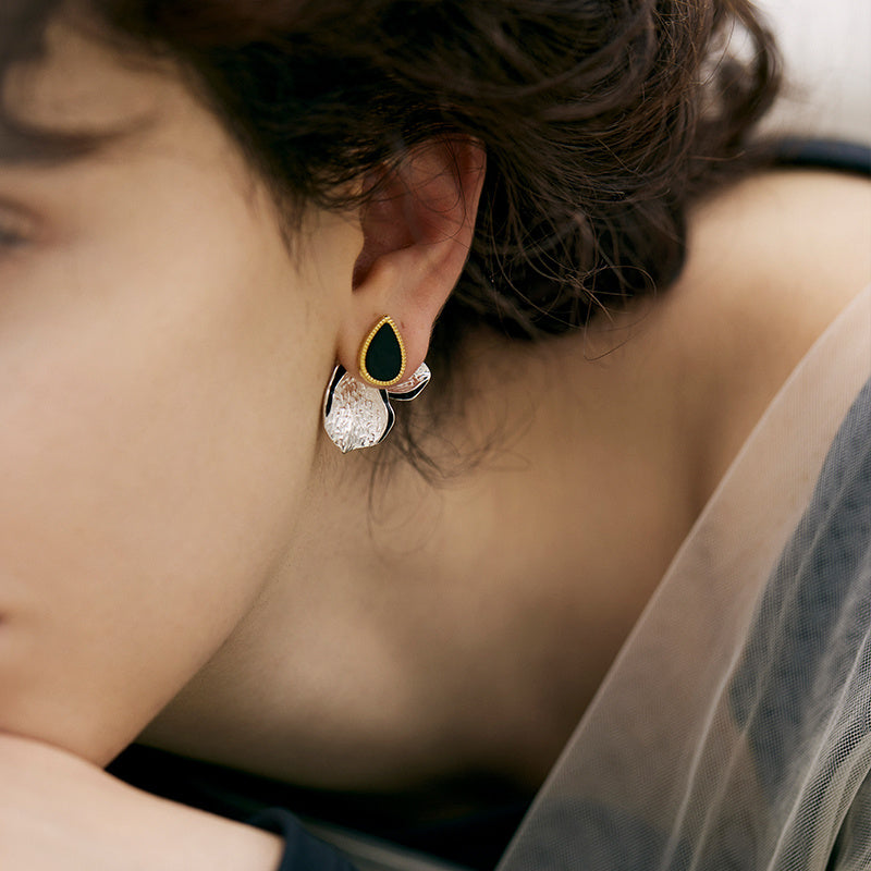 Close-up of a person wearing a green and clear earring.