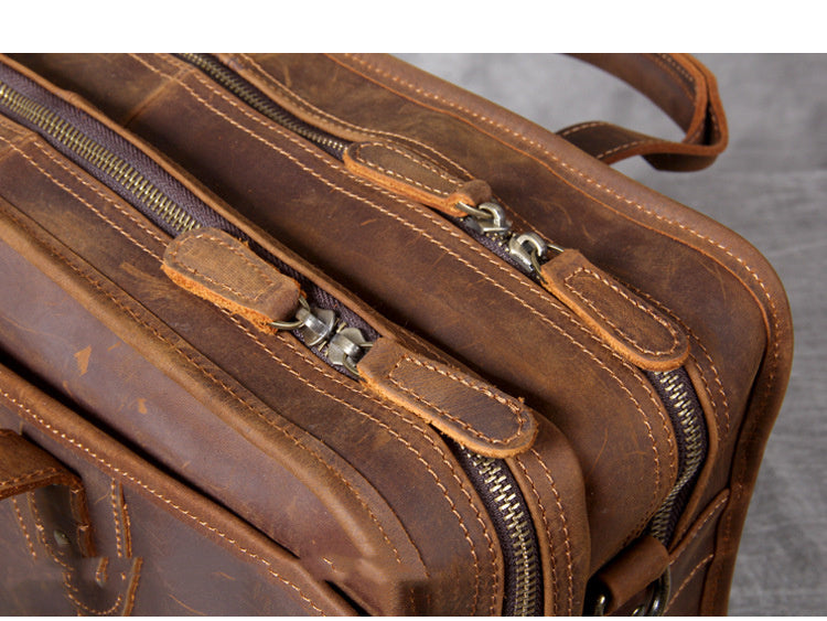 Brown leather briefcase with multiple zippers on a gray background