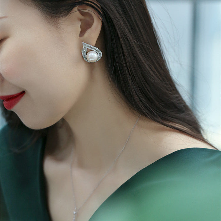 Close-up of a woman wearing pearl earrings with a blurred background