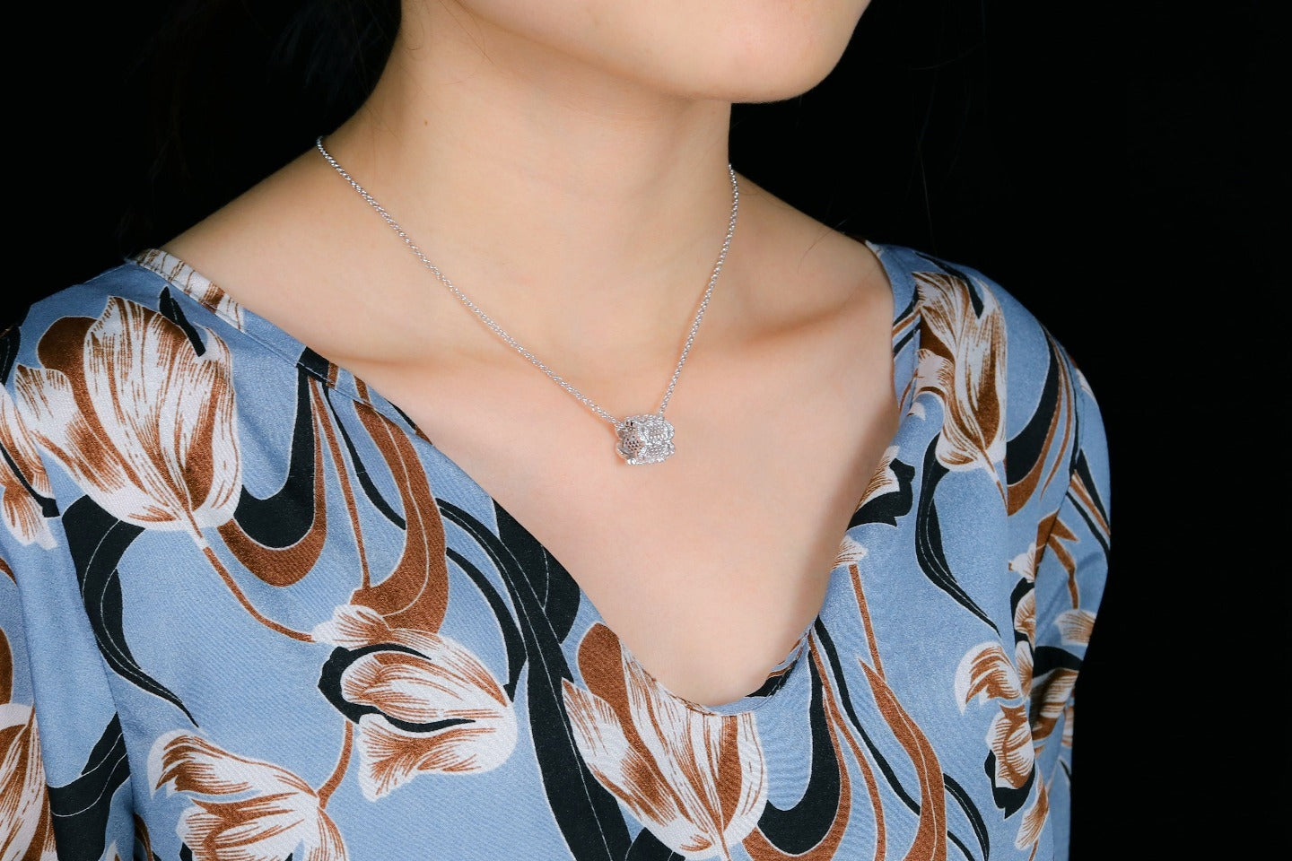 Necklace with a diamond pendant worn by a person against a dark background
