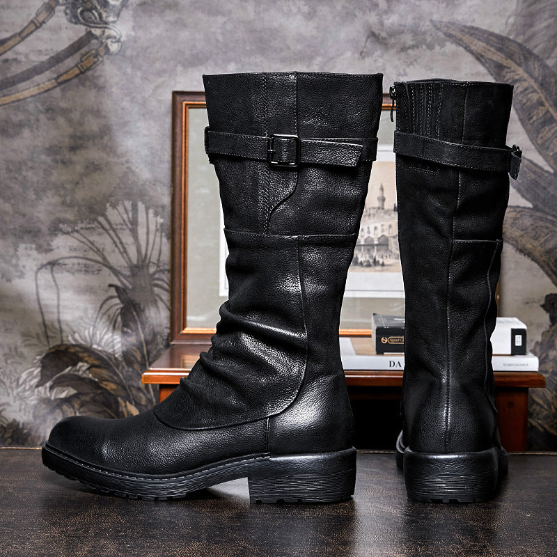 Pair of black leather boots with buckles on a textured surface.