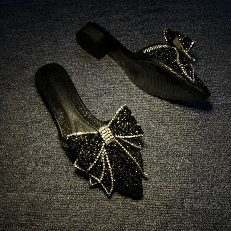 Black shoes with decorative bows on a dark textured surface