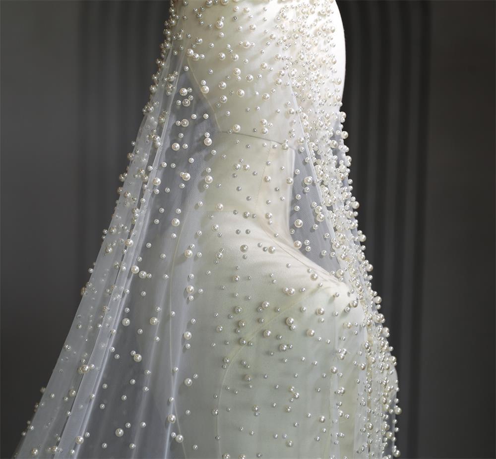 Close-up of a white wedding dress with intricate beadwork on a dark background