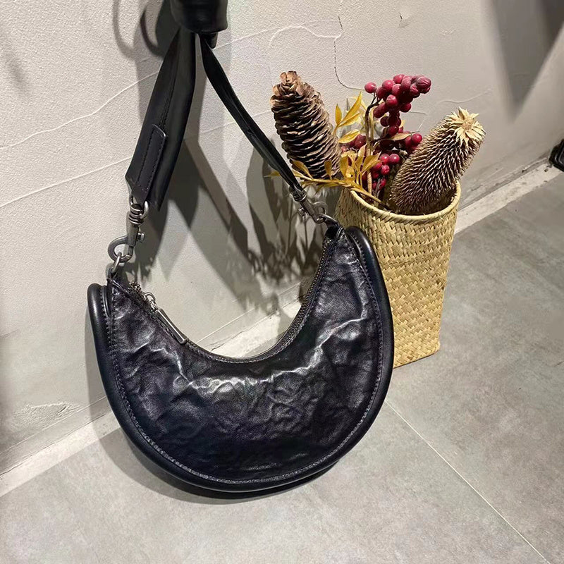 Black textured handbag on a gray floor with a woven basket containing dried plants.