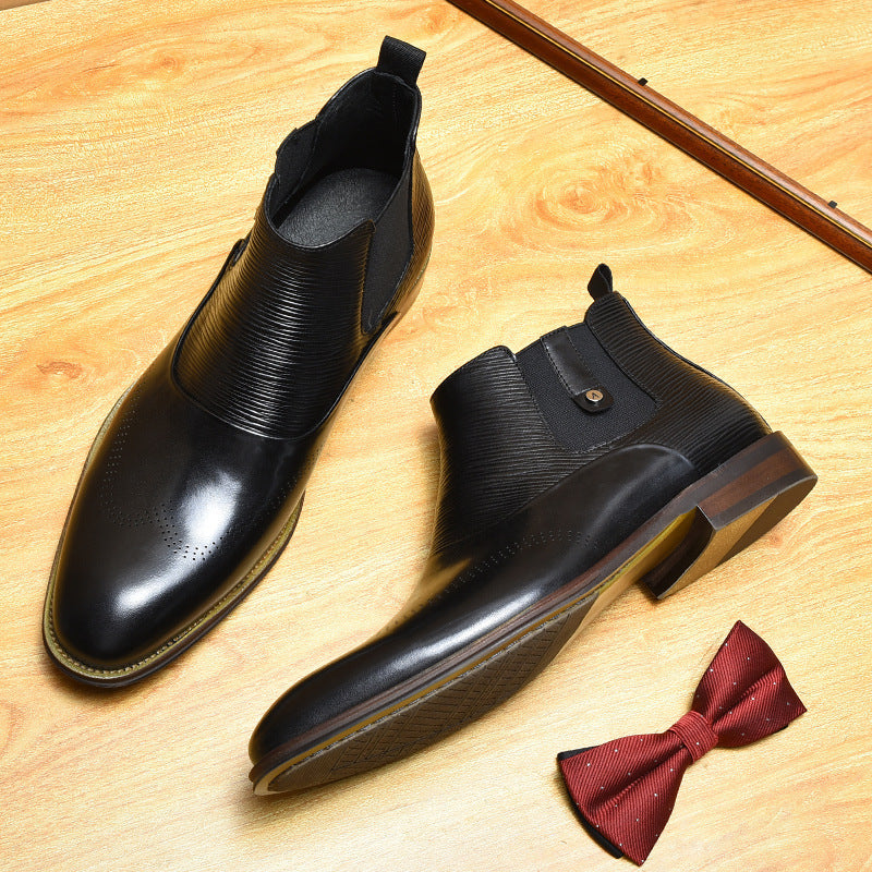 Black leather boots on a wooden surface with a red bow tie.