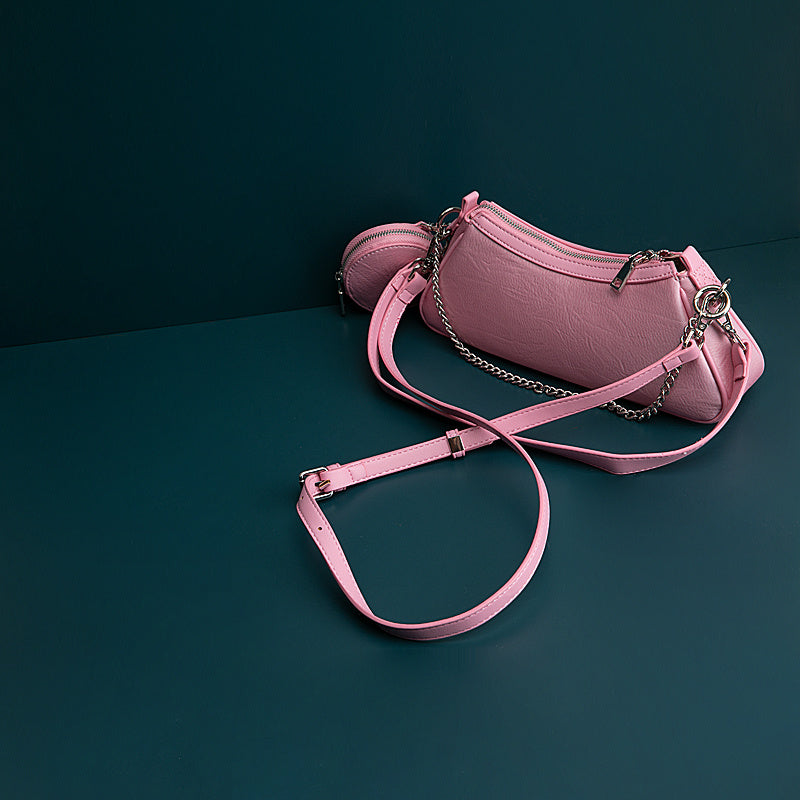 Pink handbag with a chain detail on a dark green background