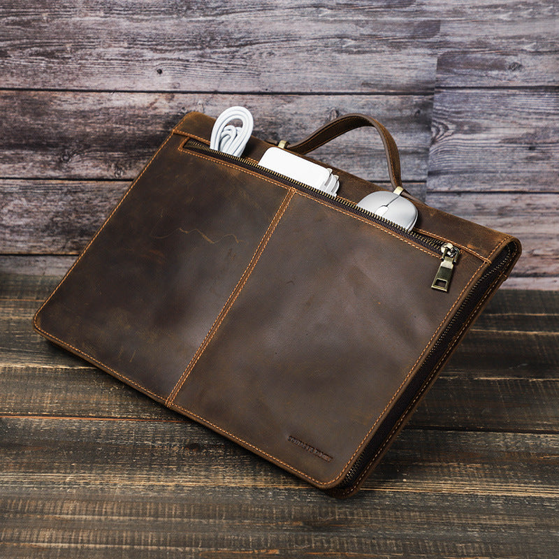 Brown leather briefcase with compartments on a wooden surface