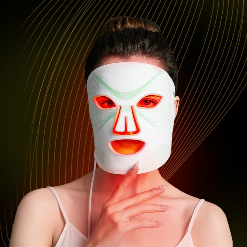 Woman wearing a LED face mask with glowing red and green lights on a dark background
