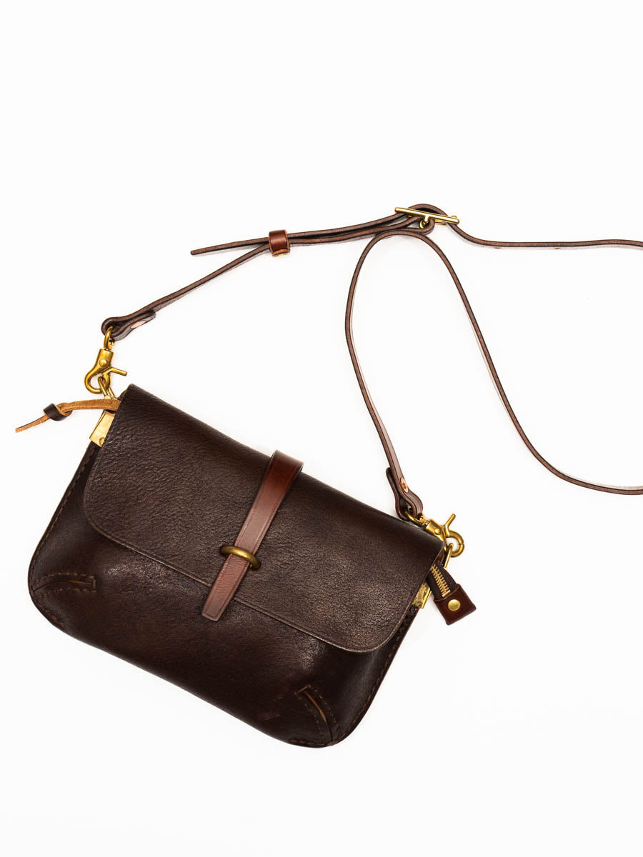 Brown leather handbag with a strap on a white background