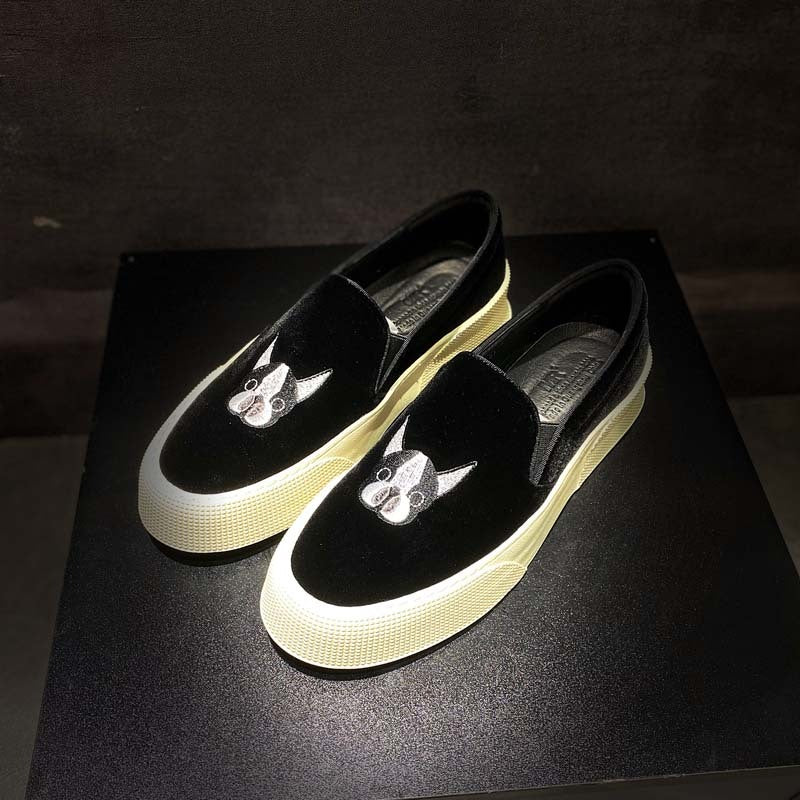 Black slip-on shoes with white soles and cat designs on a dark background