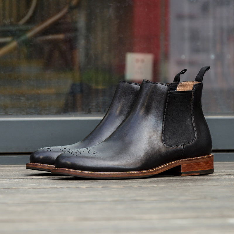 Pair of black leather Chelsea boots on a wooden surface with a blurred background
