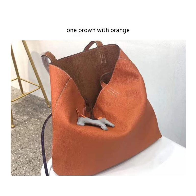 Orange leather handbag with a brown top section on a white surface.