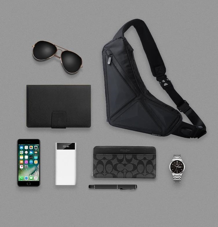 Collection of black and silver accessories including a phone, wallet, and sunglasses on a gray background