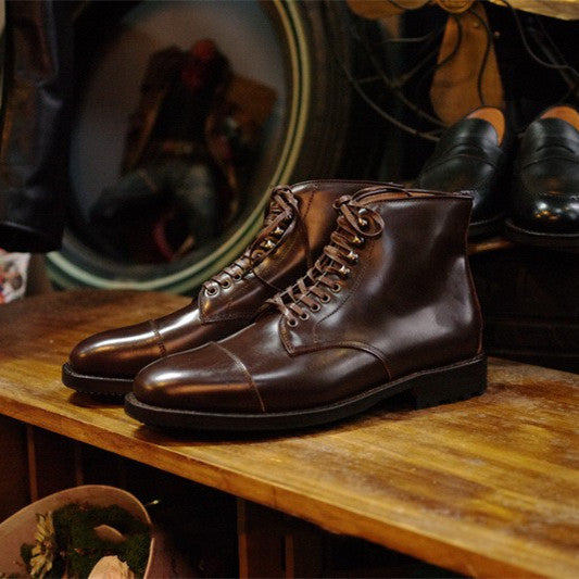 Brown leather boots on a wooden surface with a blurred background