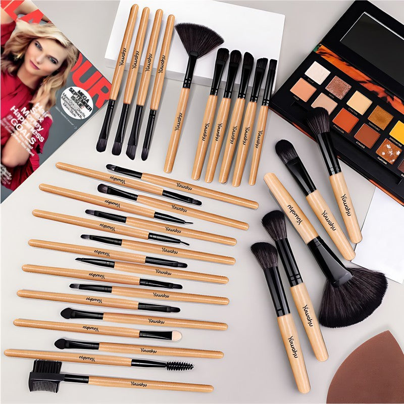 Makeup brushes and palette on a light surface with a blurred person in the corner.