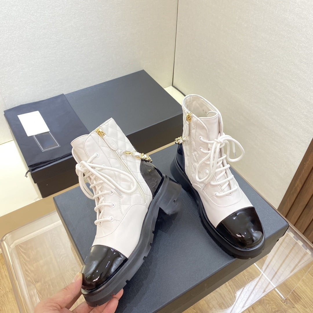 White boots with black soles on a gray surface, with a box in the background.