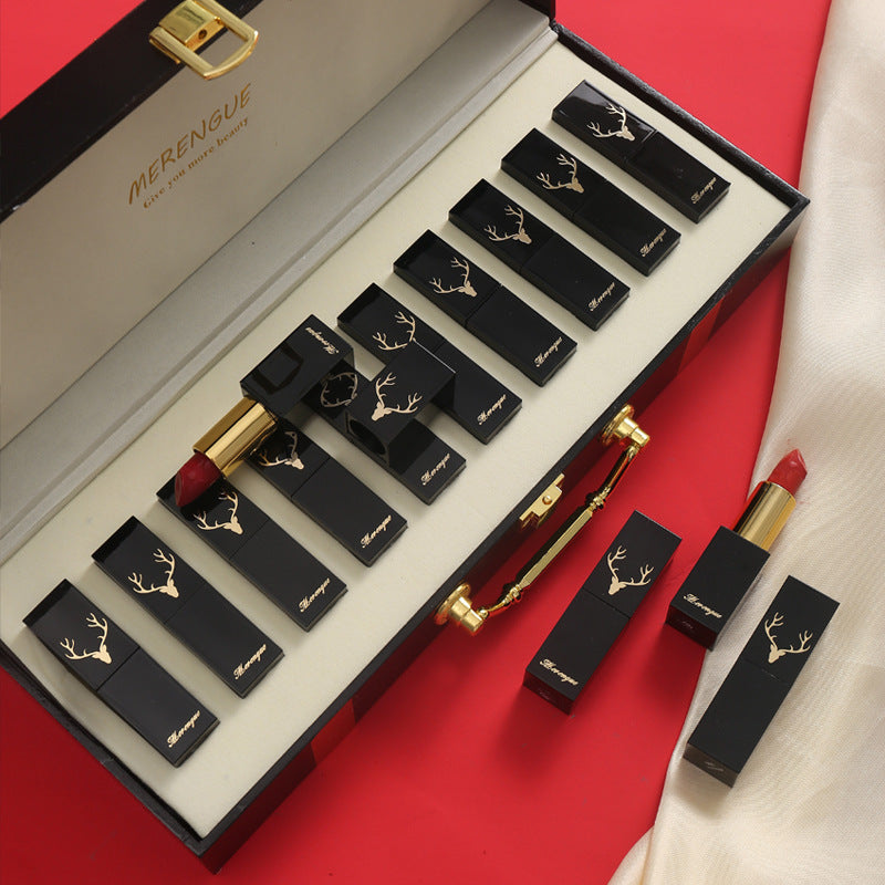 Set of black lipsticks with gold accents in a Merengue box on a red background
