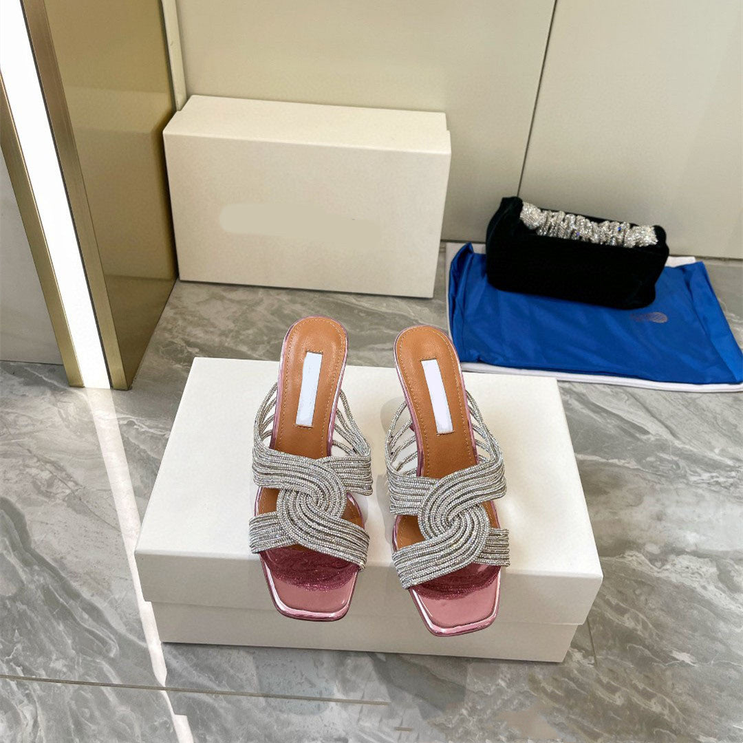 Pair of silver high-heeled sandals on a white box with a neutral background