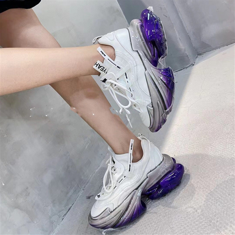 White sneakers with purple soles worn by a person on a light gray background
