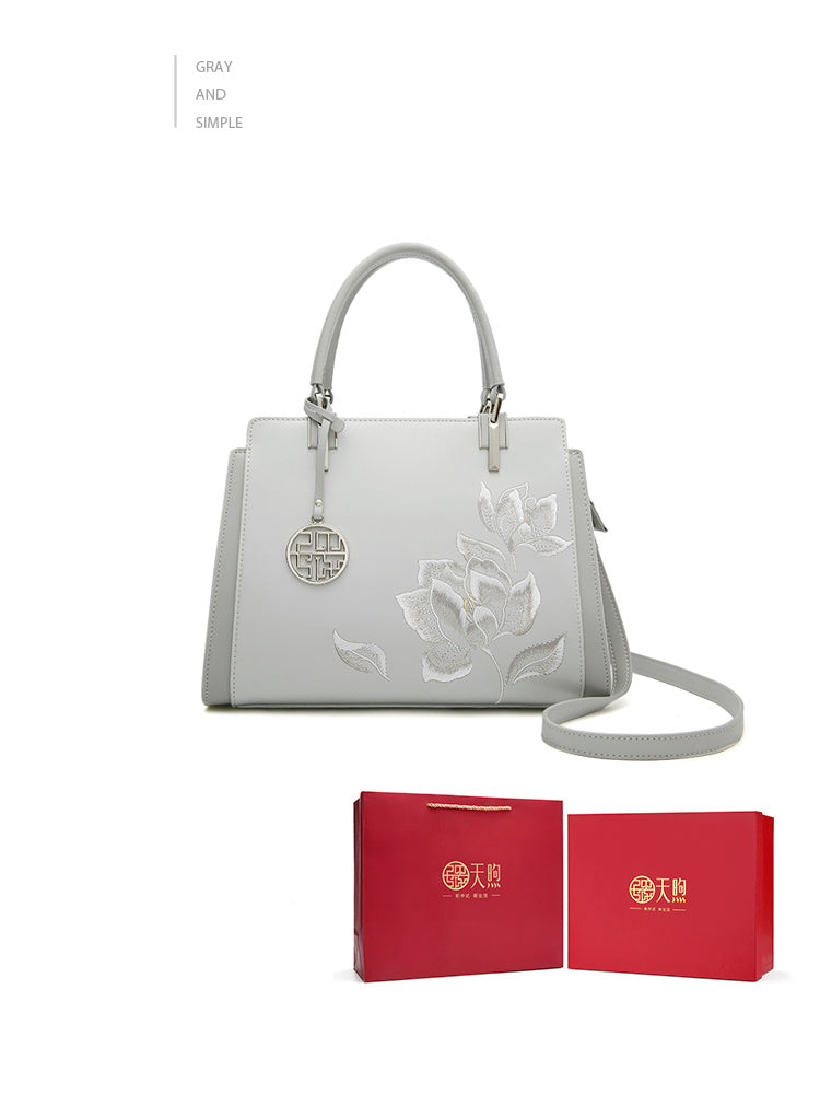 White handbag with floral design and red gift boxes on a white background