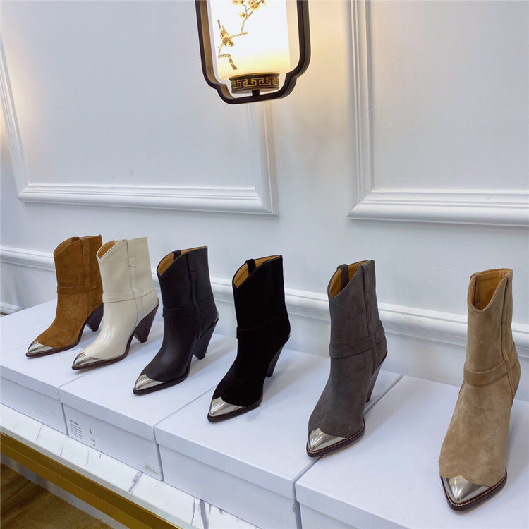Set of six pairs of women's boots displayed on a white surface with a decorative wall in the background.
