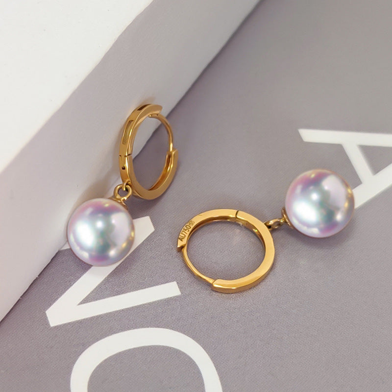 Gold hoop earrings with pearl drops on a magazine page