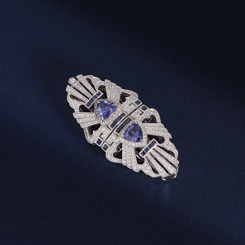 Silver brooch with purple gemstones on a dark blue background