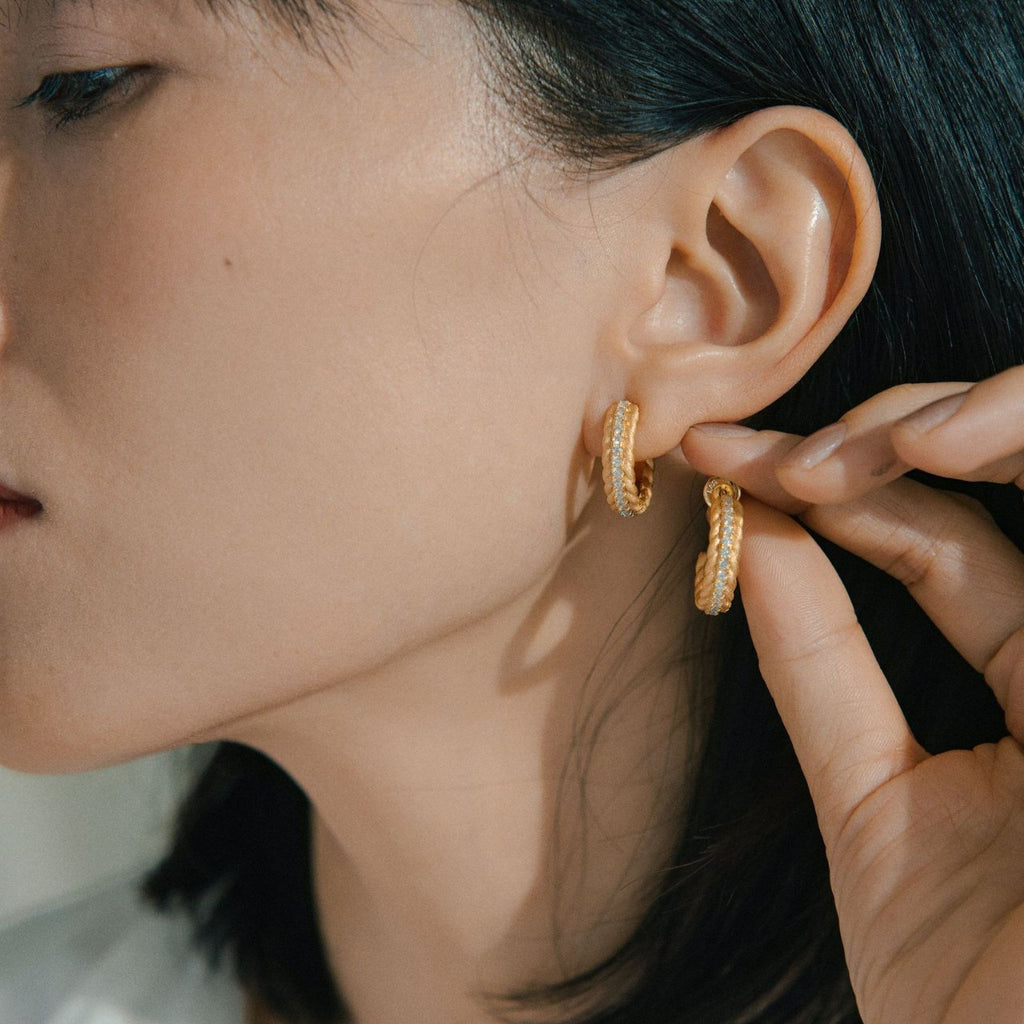 Person wearing gold hoop earrings with a close-up of the ear.