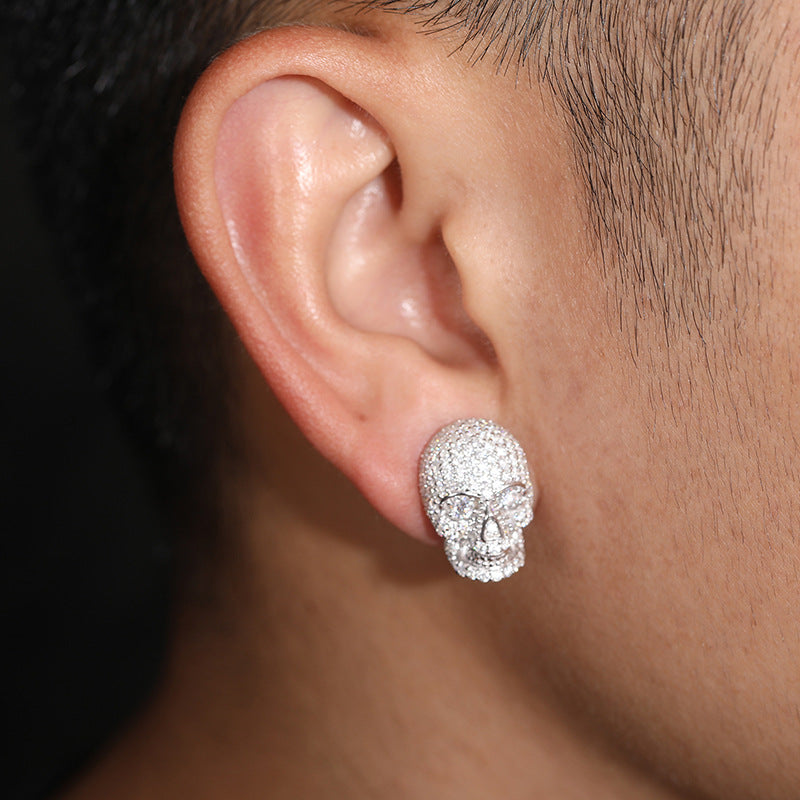 Close-up of an ear wearing a sparkling skull-shaped earring.