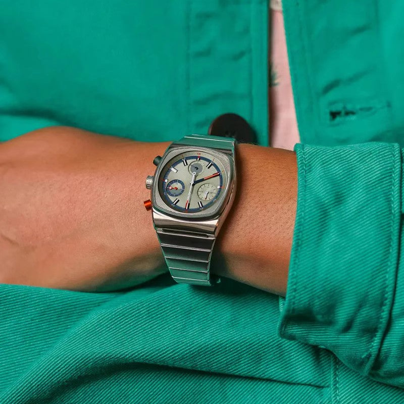 Silver wristwatch on a person's wrist with a green jacket