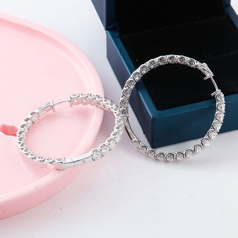 Silver hoop earrings on a pink stand with a blue jewelry box in the background