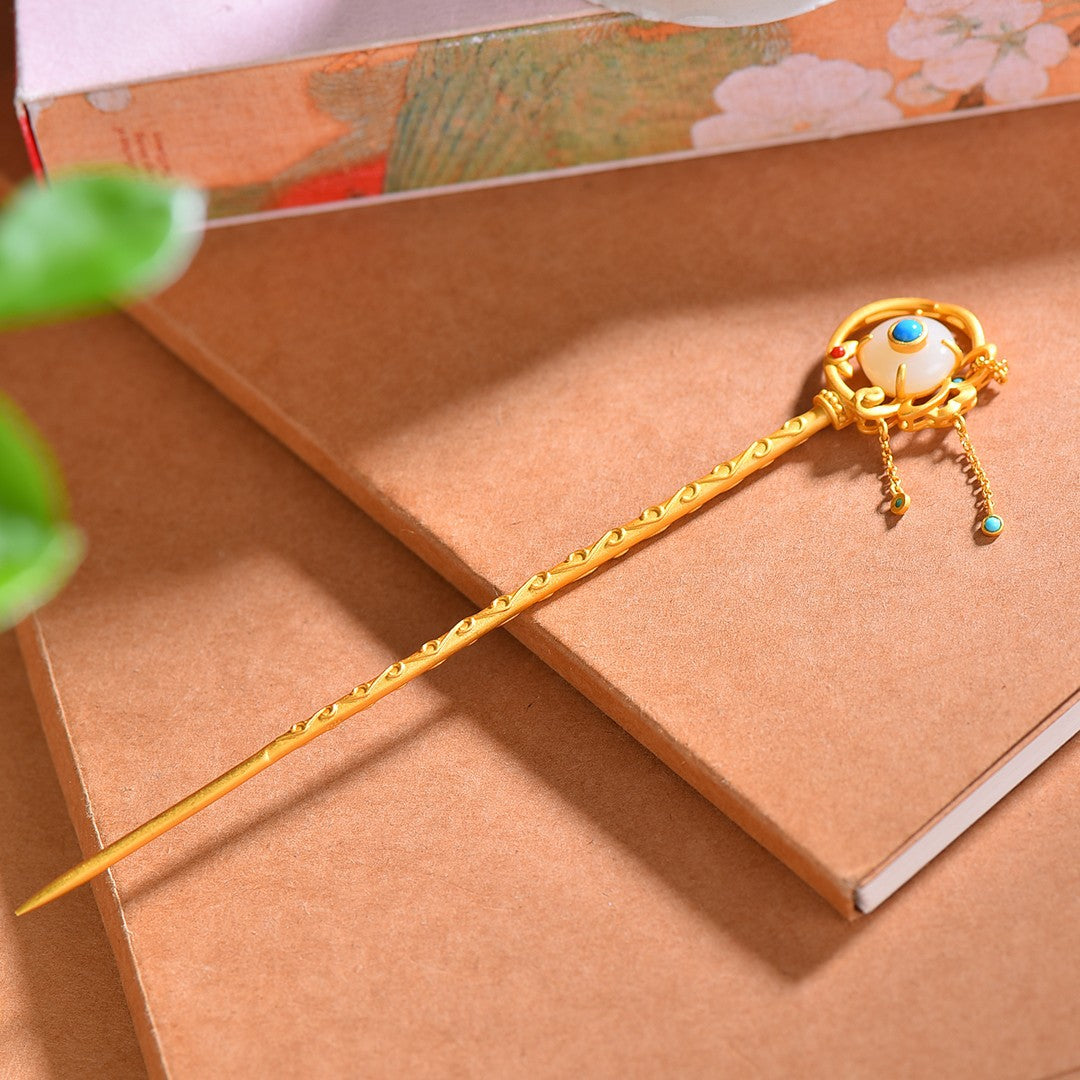 Decorative gold hairpin with gemstones on a brown surface