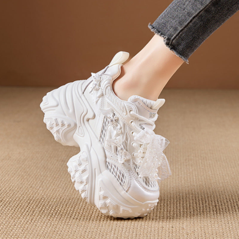 White lace-up sneaker on a beige surface with a blurred background