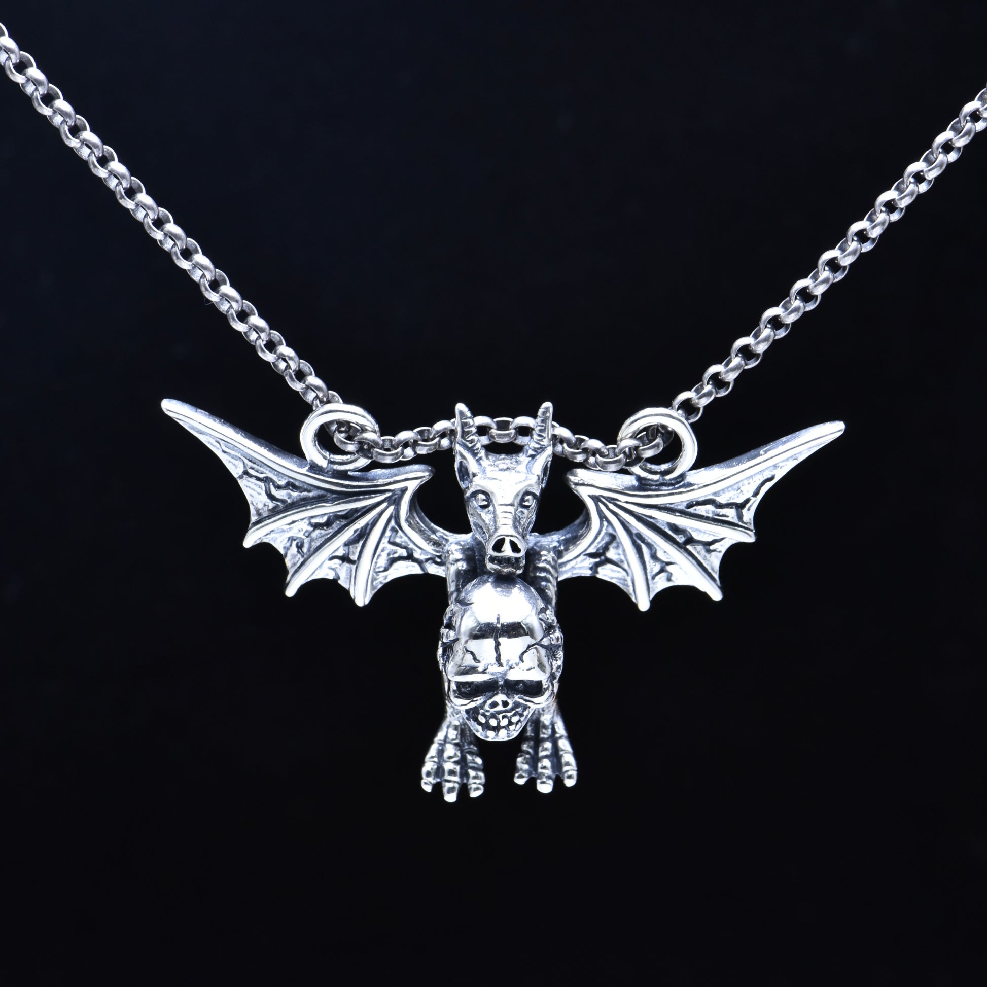 Silver bat-shaped pendant on a chain against a black background