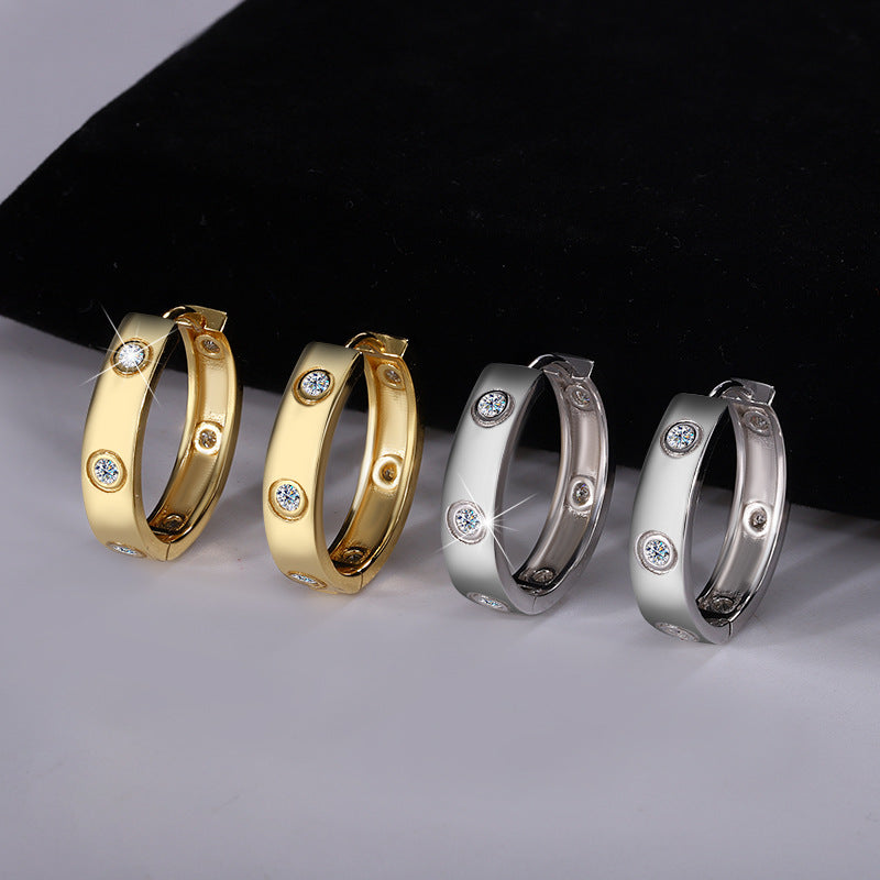 Four hoop earrings in gold and silver on a gray surface with a black background