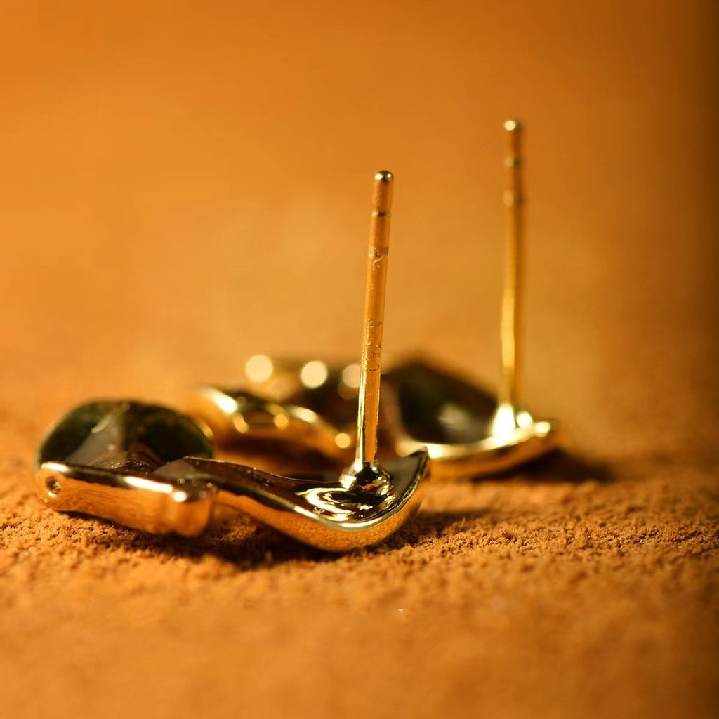 Two gold spoons on a textured brown surface with a warm color tone.