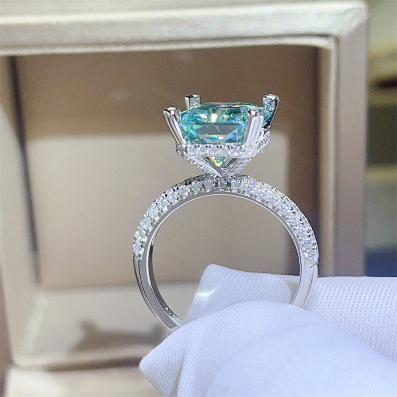 Elegant ring with a blue gemstone and diamond-studded band on a white surface.
