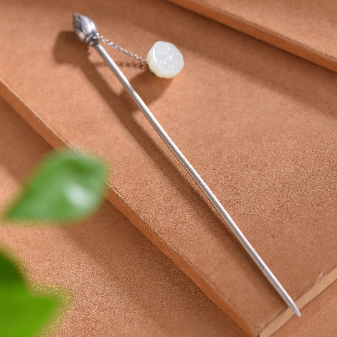 Silver hairpin with a white stone on a brown surface