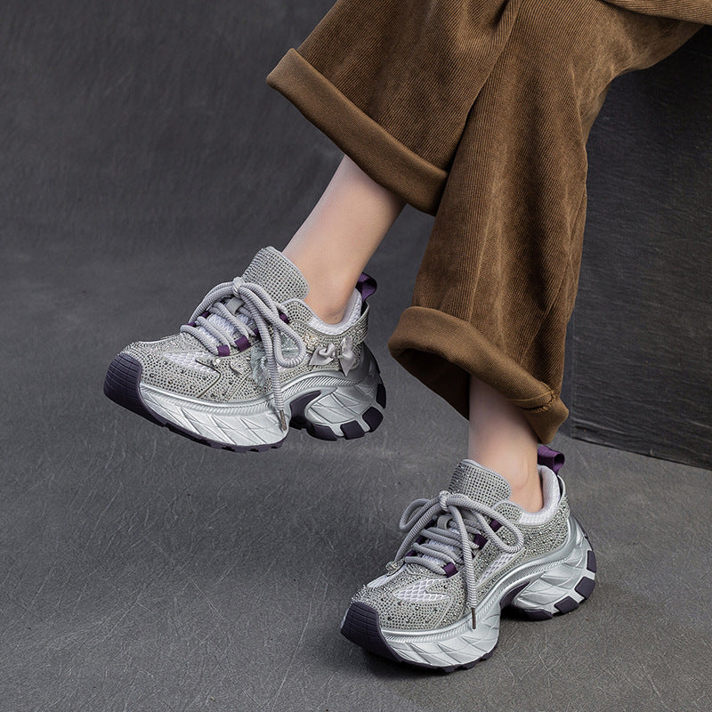 Gray sneakers worn with brown pants on a dark background