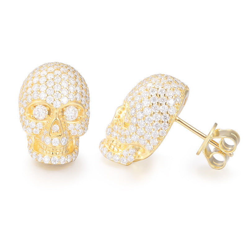 Gold skull earrings with diamond accents on a white background