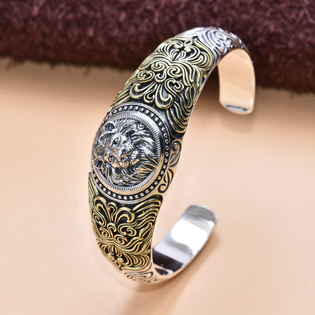 Decorative silver and gold bracelet with intricate designs on a beige background