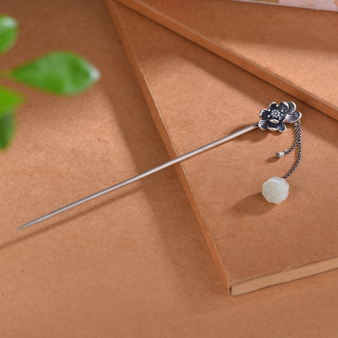 Silver hairpin with floral design and white stone on a brown surface