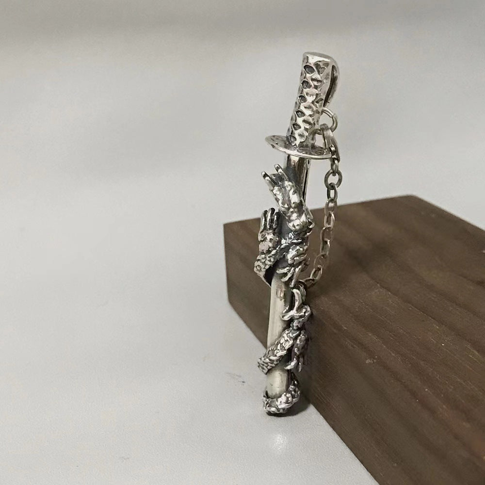 Silver dragon pendant on a chain against a neutral background