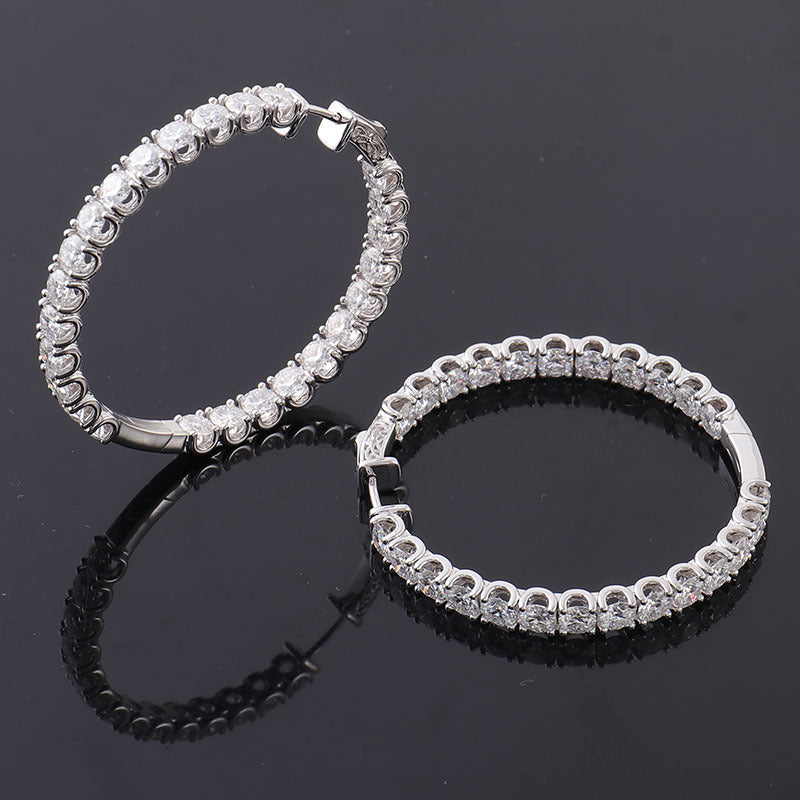 Pair of silver hoop earrings with clear stones on a black background