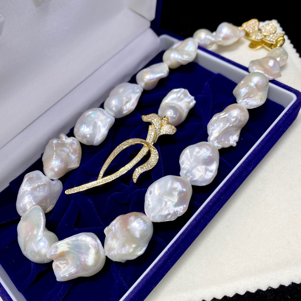 Pearl necklace with a gold pendant on a blue cushion in an open jewelry box.