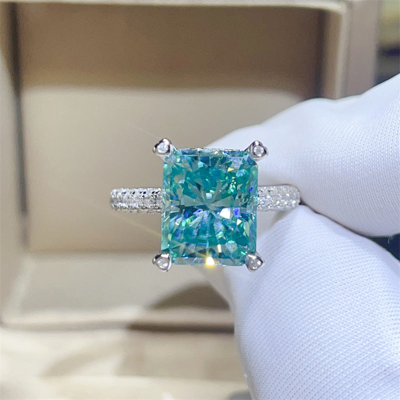 Turquoise gemstone ring with diamond accents held by a gloved hand.