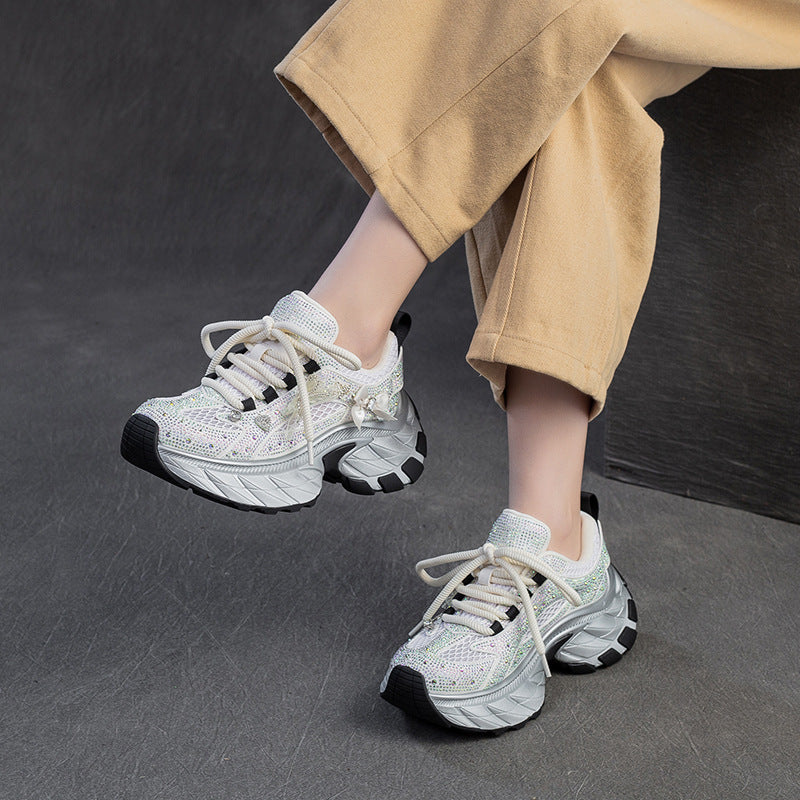 White sneakers with black accents worn by a person on a dark background