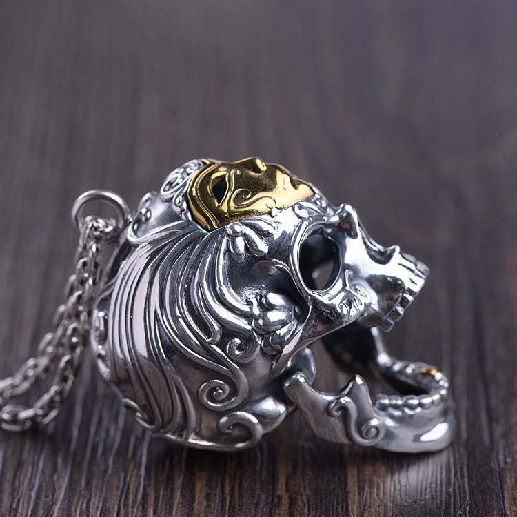 Silver and gold lion head pendant on a wooden surface