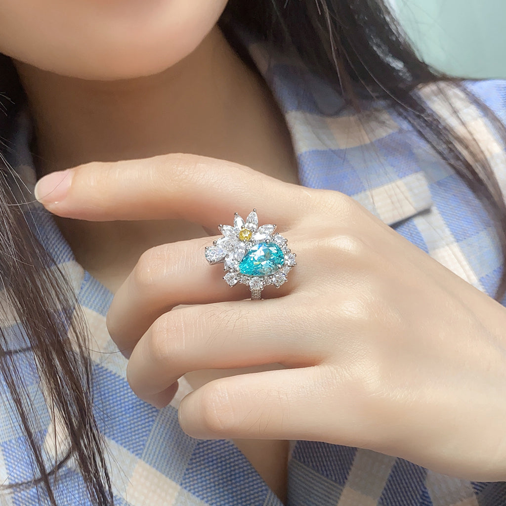 Close-up of a hand wearing a ring with a blue gemstone and diamond accents.