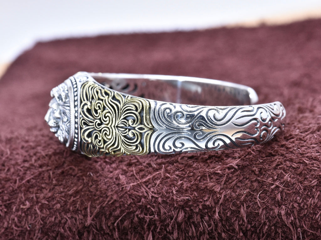 Silver bracelet with intricate designs on a brown textured surface